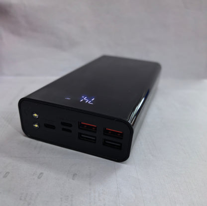 Black portable power bank with digital battery indicator and multiple USB ports on white surface