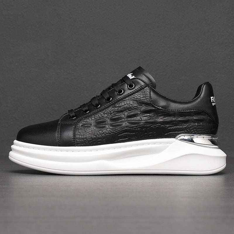 Black textured leather sneaker with white thick sole and metallic silver heel detail on gray background