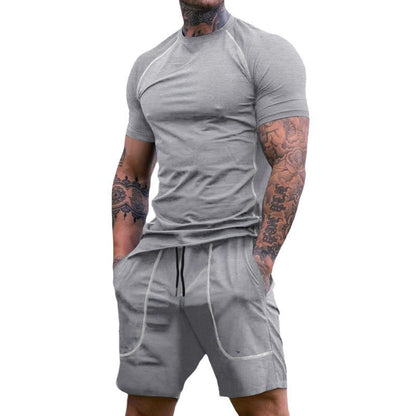 Muscular man with tattoos wearing fitted light gray short-sleeve athletic t-shirt and matching shorts with pockets