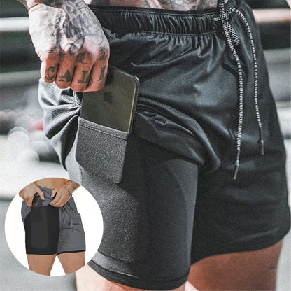 Man wearing black athletic shorts with built-in pocket holding a smartphone, featuring tattooed hand and drawstring waistband