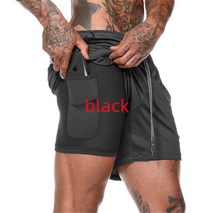 Tattooed man wearing black athletic shorts with back pocket holding a smartphone