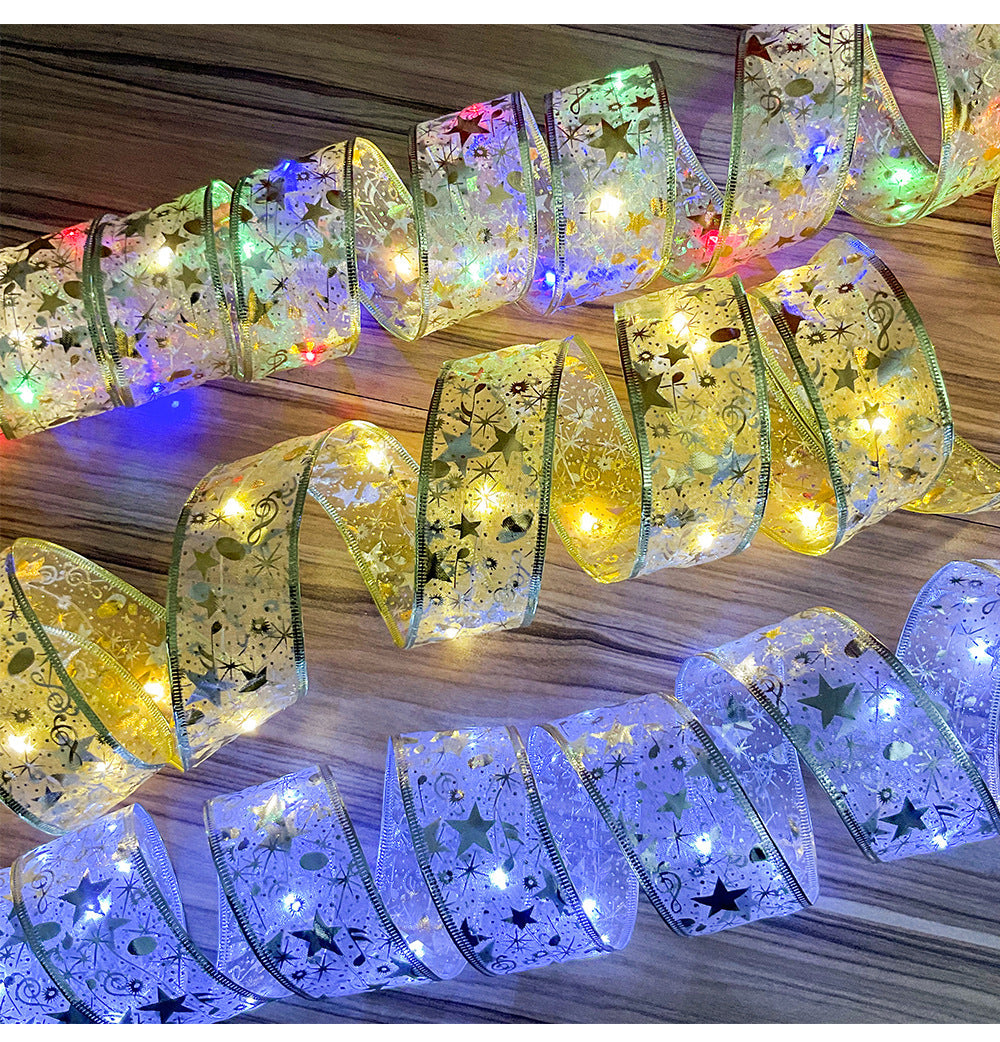 Decorative translucent ribbon with gold stars, musical notes, and colorful LED fairy lights on wood