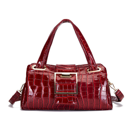 Glossy red crocodile leather handbag with double handles and large gold buckle detail