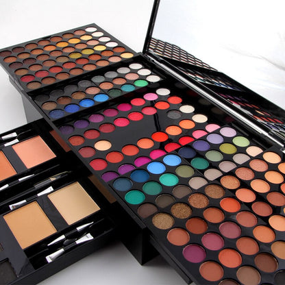 Open colorful makeup palette featuring diverse eyeshadow shades, blushes, and contour powders with applicator brushes