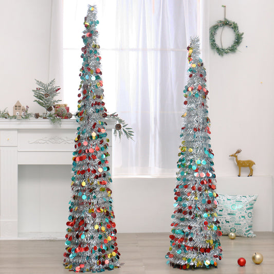 Two tall silver tinsel Christmas trees decorated with red, yellow, and blue circular ornaments in a bright room