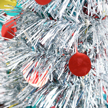 Close-up of silver tinsel Christmas tree branches with colorful round paper ornaments in red, yellow, and blue