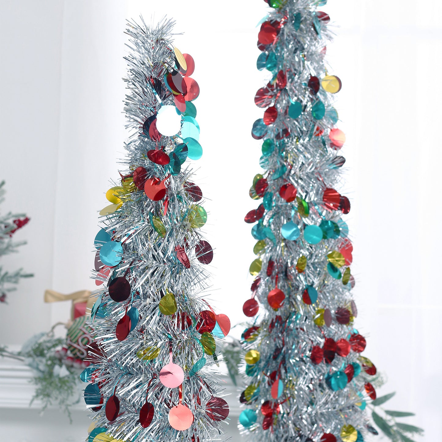 Silver tinsel Christmas trees decorated with shiny red, blue, and yellow round sequins indoors