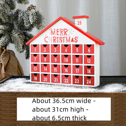 Wooden Christmas advent calendar shaped like a house with 24 red numbered drawers and festive 'Merry Christmas' text