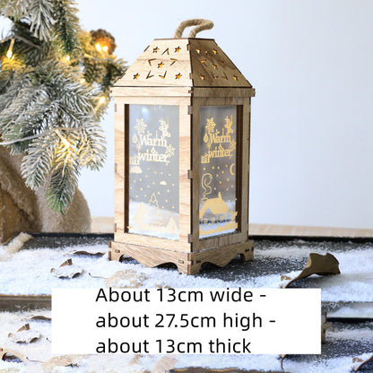 Wooden Christmas lantern with warm white holiday illustrations, placed on snowy surface near frosted pine branch