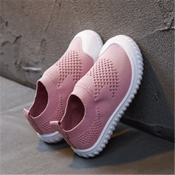 Pink toddler slip-on shoes with breathable knit fabric and white flexible soles on gray background