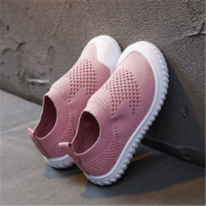 Pink toddler slip-on shoes with breathable knit fabric and white flexible soles on gray background
