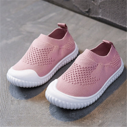 Pink toddler slip-on shoes with breathable knit upper and flexible white soles on concrete floor
