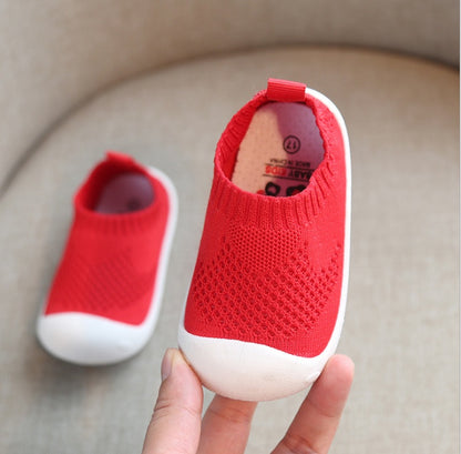 Pair of red toddler slip-on shoes with white soft soles and breathable knit cotton design