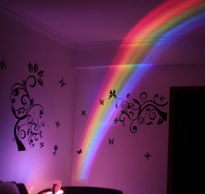 colorful rainbow light projection on pink wall with black butterfly and tree decals in room