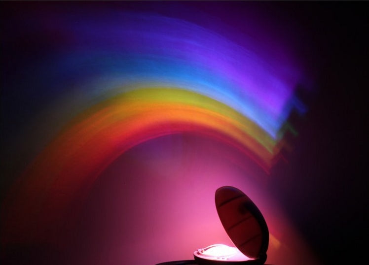 Rainbow LED projector night light creating multicolored arch pattern on dark wall