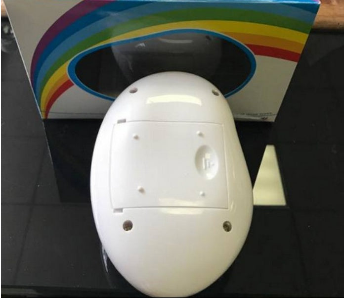 White oval-shaped rainbow projector night light on black surface with rainbow-themed packaging