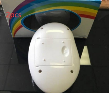 White oval-shaped electronic device with battery compartment on black surface, rainbow-striped packaging in background