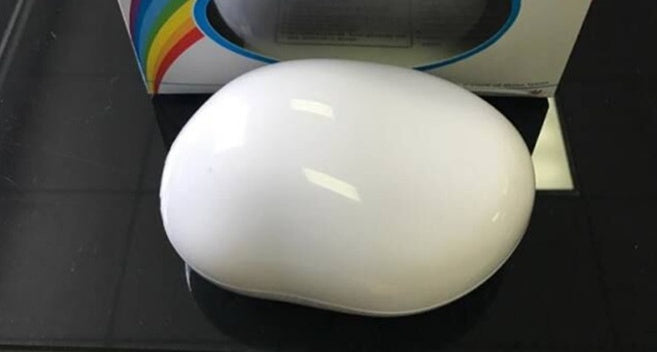 White smooth oval rainbow projector night light on a reflective black surface with colorful packaging