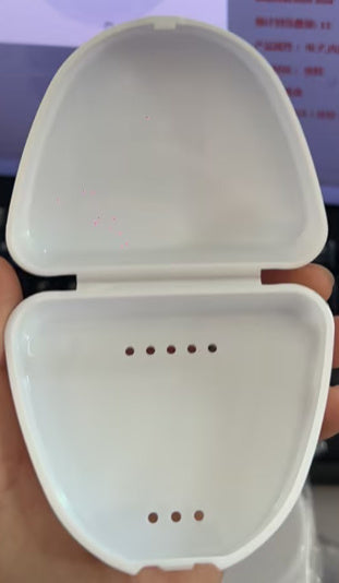 Open white plastic case with ventilation holes, held in hand against blurred background