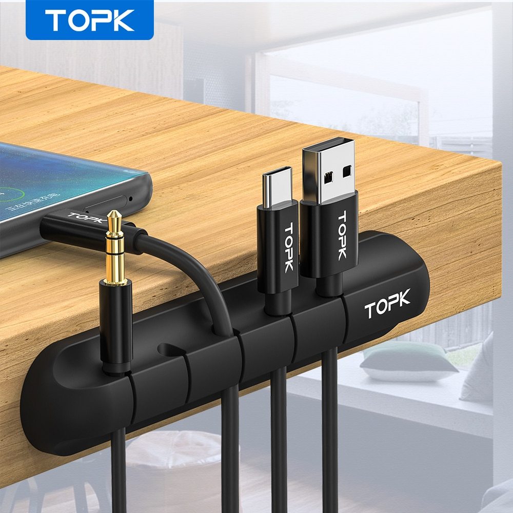Black silicone TOPK cable organizer holding USB, USB-C, and audio cables on wooden desk edge