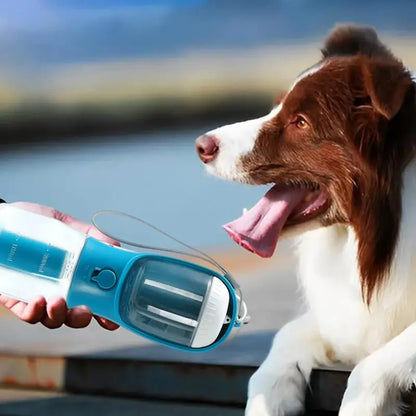 Brown and white dog with tongue out near blue portable pet water bottle and feeder with built-in water filter