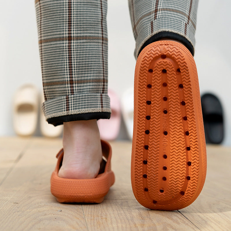 Person wearing orange EVA platform slippers with textured sole and plaid pants on wooden floor