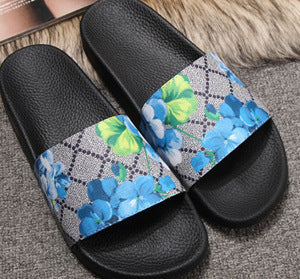 Trendoligy women's black PVC slide sandals with blue and green floral patterned straps on gray carpet