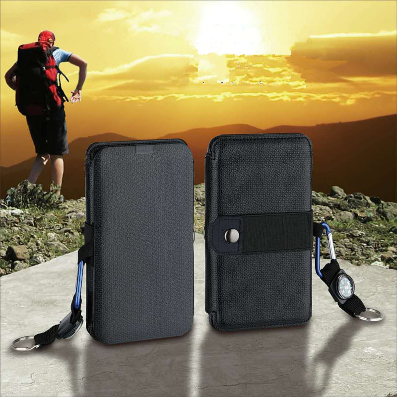 Black portable solar chargers with textured cases, carabiners, and compasses against a sunset hiking backdrop