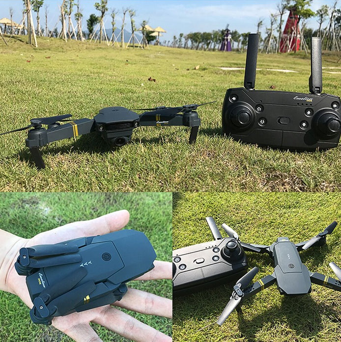 Black compact quadcopter drone with camera and remote control on grass in bright outdoor park