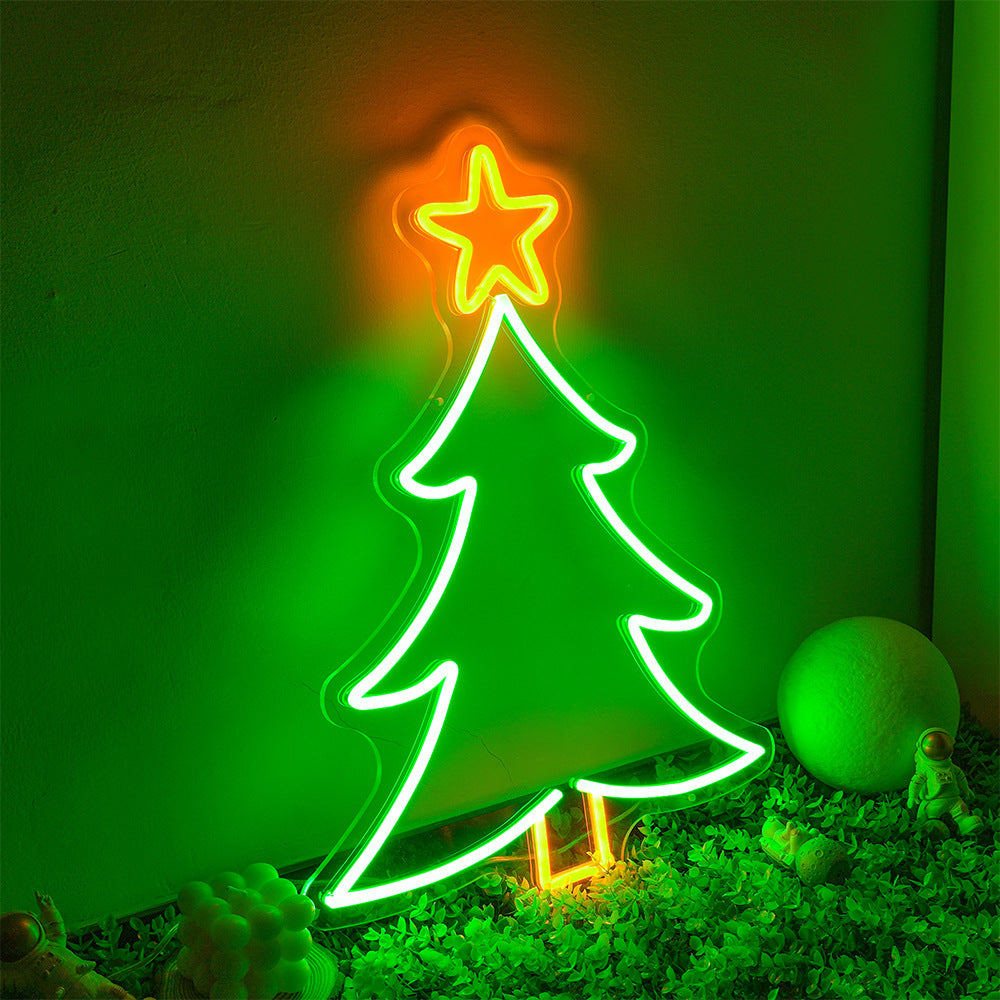 Neon Christmas tree sign with glowing green outline and orange star on top, indoor decoration