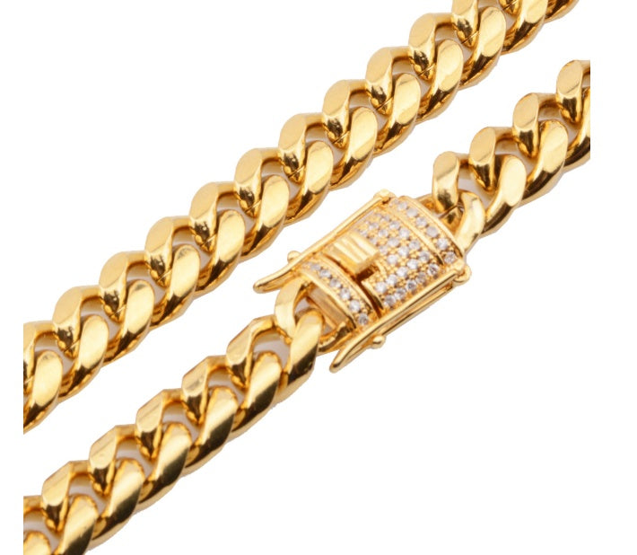 Close-up of chunky gold Cuban link chain necklace with diamond-studded clasp on white background