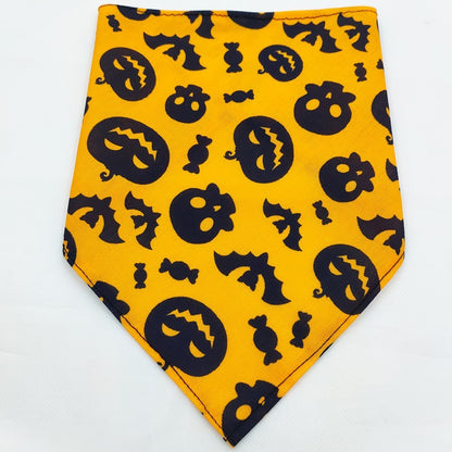 Orange dog bandana with black Halloween motifs including pumpkins, skulls, bats, and candies