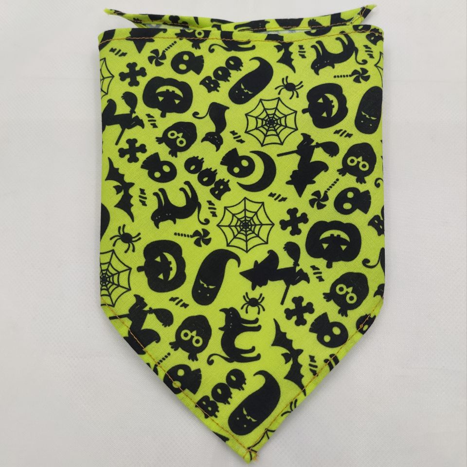 Bright green dog bandana with Halloween-themed black print including cats, pumpkins, bats, and spider webs