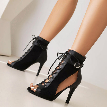 Black lace-up stiletto heel ankle boots with peep-toe and buckle detail on model's feet