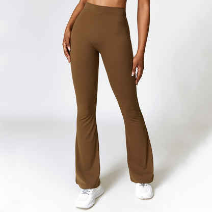 Woman wearing brown high-waist bootcut fitness pants with white sneakers on white background