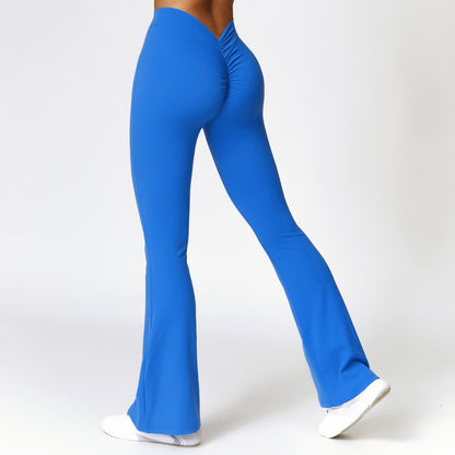 Woman wearing blue high-waist bootcut fitness pants with scrunched back detail and white sneakers