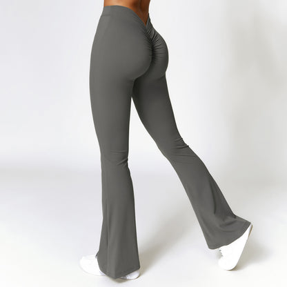 Woman wearing gray high-waist bootcut fitness pants with scrunched back detail and white sneakers
