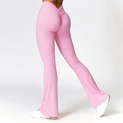 Woman wearing pink high-waist fitness pants with scrunch detail and white sneakers on white background