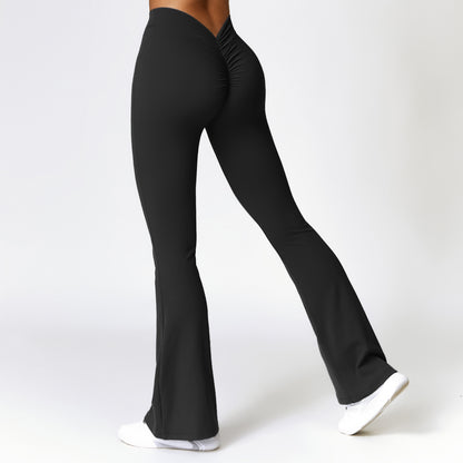 Back view of woman wearing black high-waist bootcut fitness pants with ruched detail, white sneakers