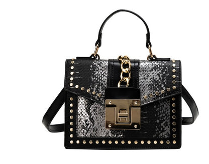 Black and silver snakeskin leather crossbody bag with gold studs, chain, and lock detail