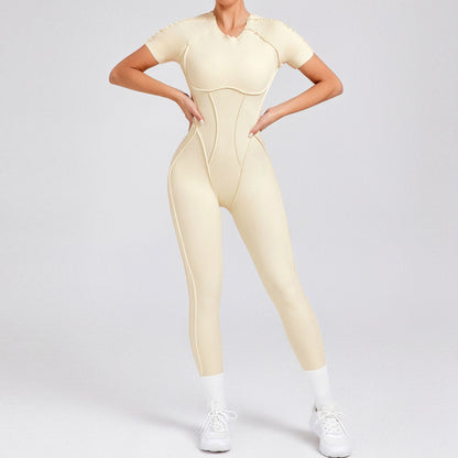 Woman wearing beige short-sleeve yoga jumpsuit with white sneakers and socks on gray background