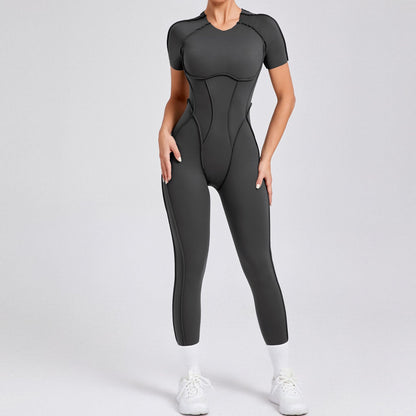 Woman wearing black seamless athletic jumpsuit with white sneakers on gray background