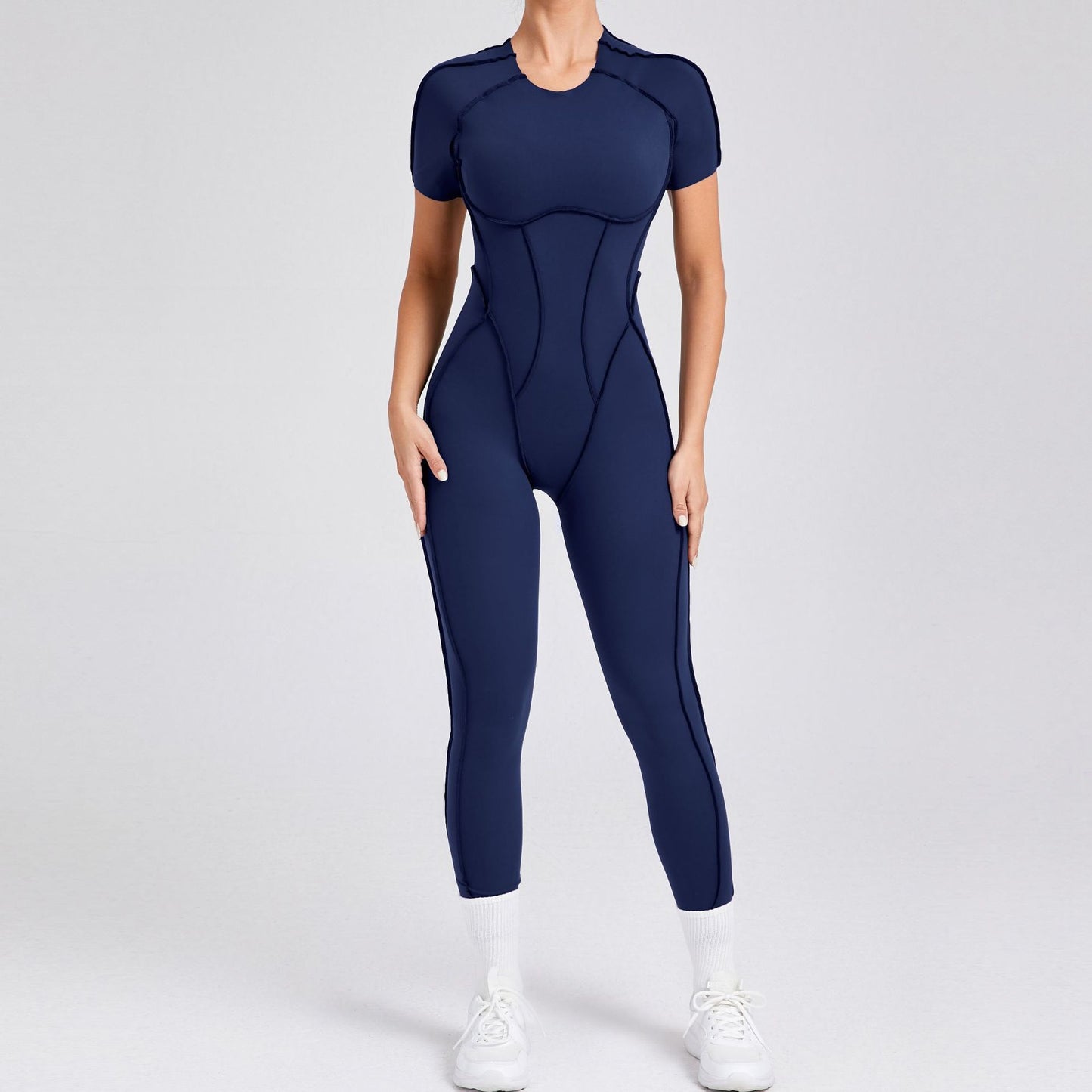 Woman wearing navy blue fitted athletic jumpsuit with short sleeves and white sneakers