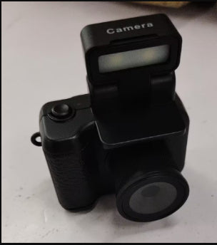 black compact digital camera with pop-up flash on white surface