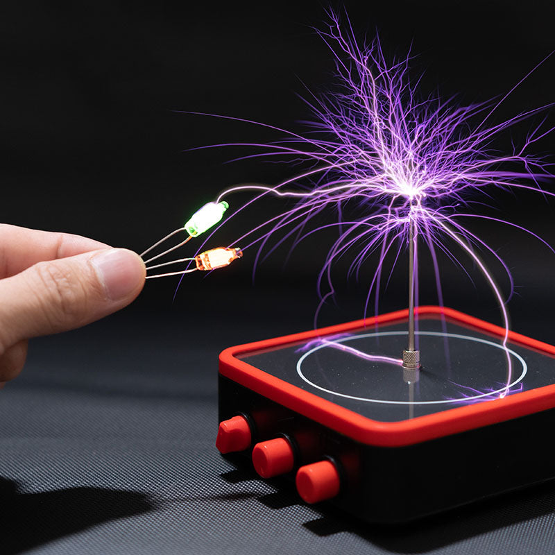 Hand holding LEDs near a black and red Tesla coil physics toy emitting purple electrical arcs