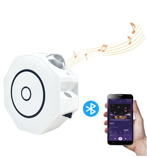 White Bluetooth speaker with star projector and music notes, connected to smartphone playing music
