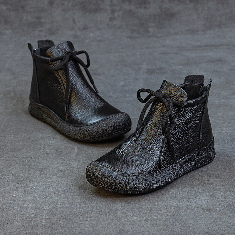 Pair of black women's leather ankle boots with laces on gray surface