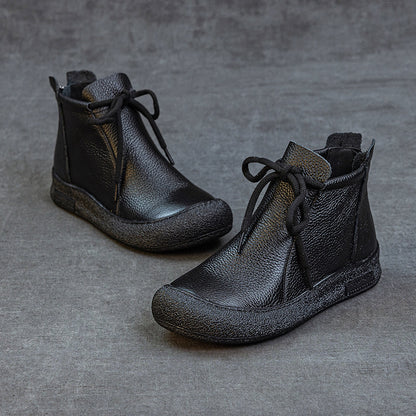 Pair of black women's leather ankle boots with laces on gray surface