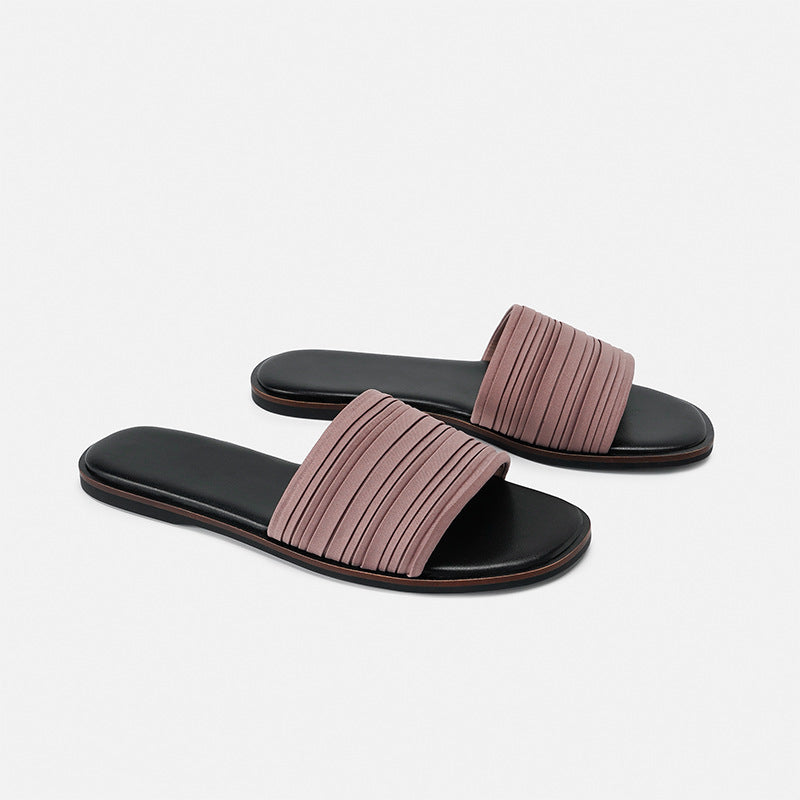 Pair of women's flat slide sandals with black footbed and mauve pleated strap