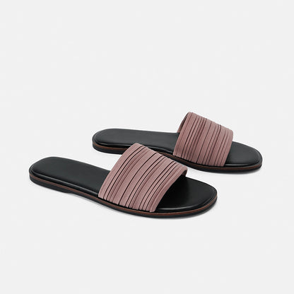Pair of women's flat slide sandals with black footbed and mauve pleated strap